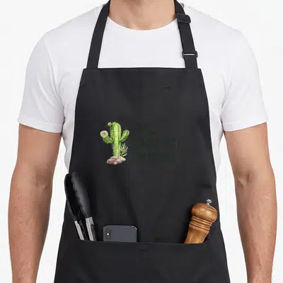 Nope honestly apron - Green cactus with rocks and text saying NOPE REALLY NOT A HUGGER — shown on a black cotton canvas apron against a white background