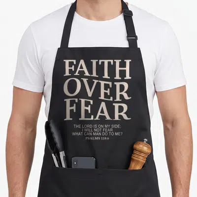 Faith fear christian apron - Stacked grey typography reading Faith Over Fear and Psalms 118:6 — shown on a black cotton canvas apron against a white background