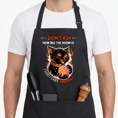 Didnt cat apron - Black cat holding orange d20 die surrounded by flames with I didn't ask how big the room is said I — shown on a black cotton canvas apron against a white background