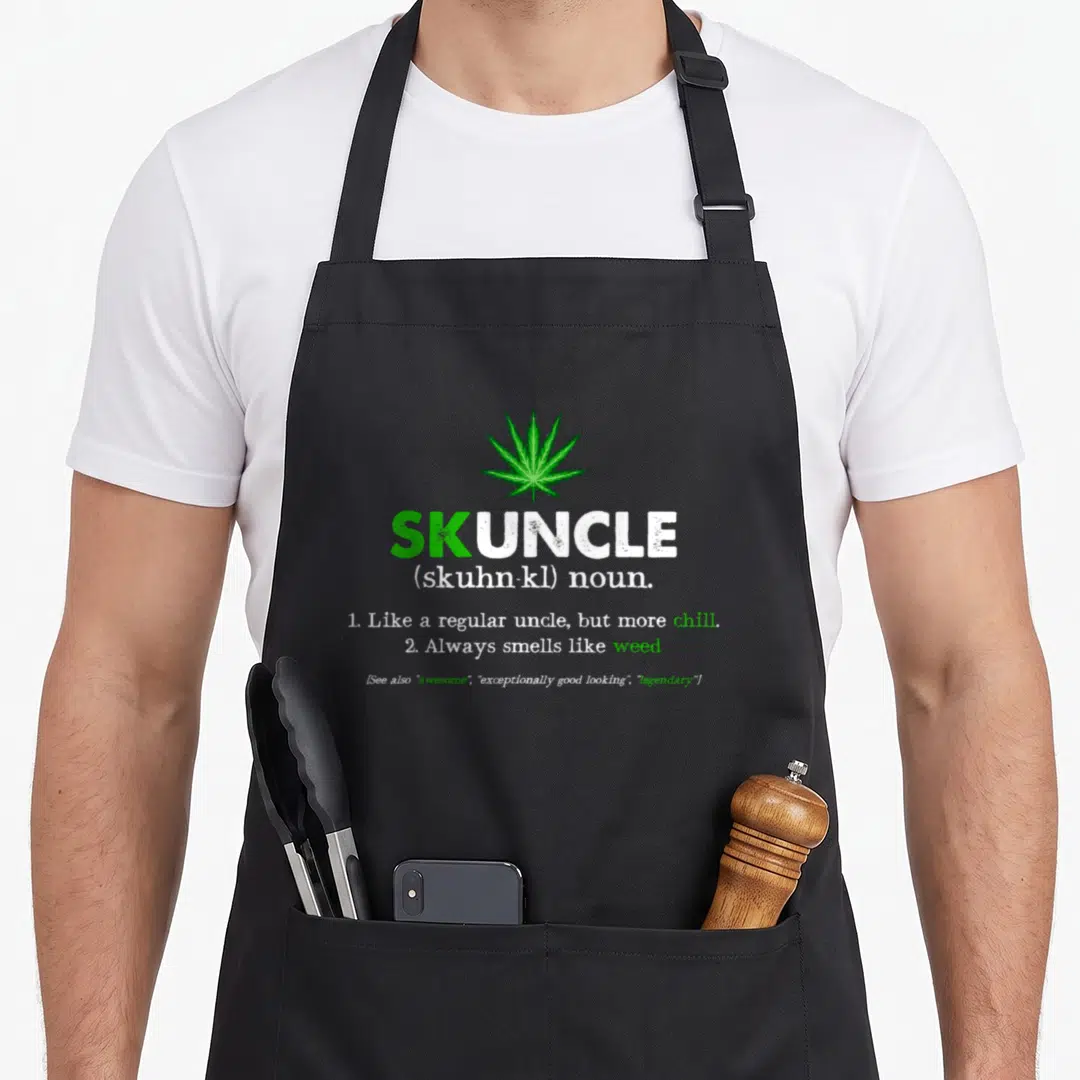 Skuncle smoker apron - Green cannabis leaf above white and green dictionary definition of skuncle — shown on a black cotton canvas apron against a white background
