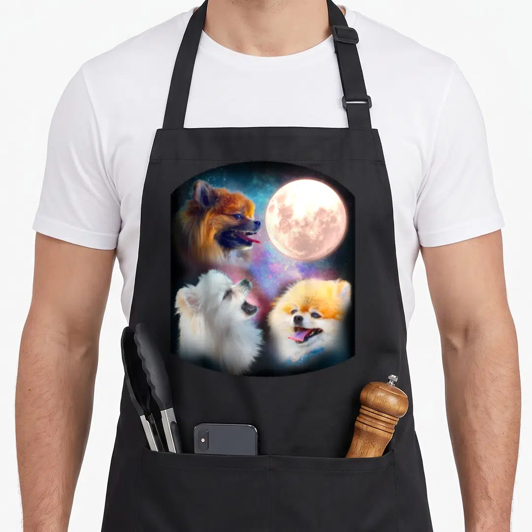 Pomeranian dog apron - Three Pomeranians and full moon against orange white blue purple nebula — shown on a black cotton canvas apron against a white background