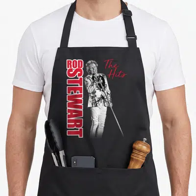 Las rod apron - Rod Stewart singing microphone photo with vertical red text and script The Hits — shown on a black cotton canvas apron against a white background