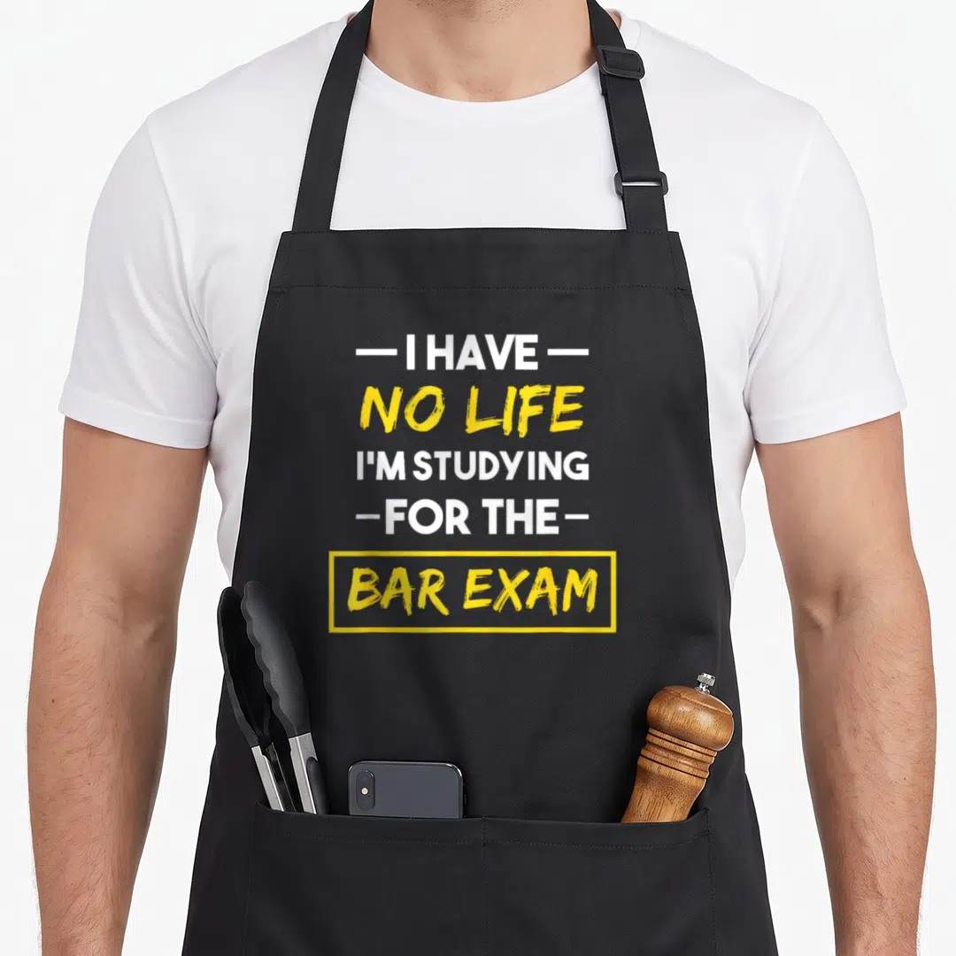 Bar exam life apron - I HAVE NO LIFE I'M STUDYING FOR THE BAR EXAM text in white and yellow — shown on a black cotton canvas apron against a white background