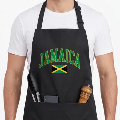 Jamaica flag jamaican apron - Arched JAMAICA text in green above a green yellow and black flag — shown on a black cotton canvas apron against a white background