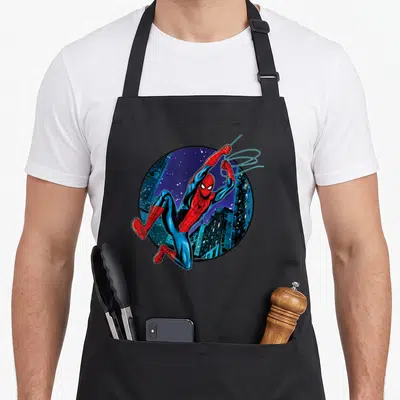 Way swing apron - Spider-Man leaping from circular night city skyline in red blue and black cartoon style — shown on a black cotton canvas apron against a white background