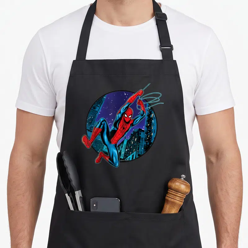 Way swing apron - Spider-Man leaping from circular night city skyline in red blue and black cartoon style — shown on a black cotton canvas apron against a white background