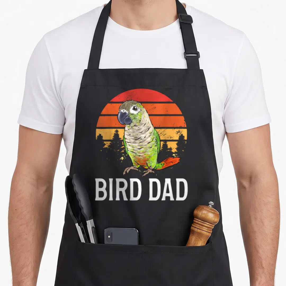 Conure parrot bird apron - Retro parrot on striped sun with BIRD DAD text in white block letters — shown on a black cotton canvas apron against a white background