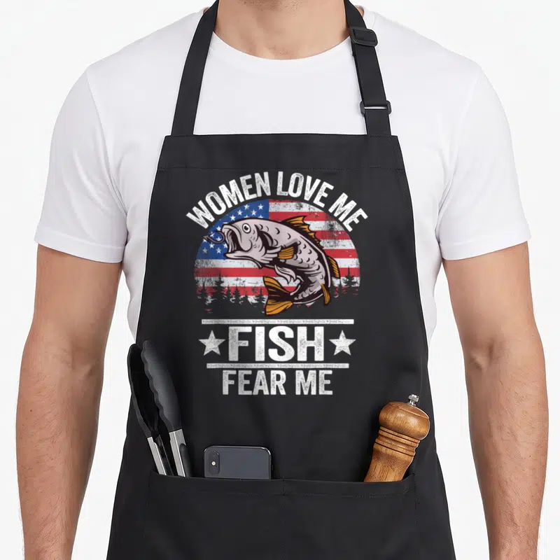Fear bass fish apron - Distressed USA flag with a hooked bass and white text reading Women Love Me Fish Fear Me — shown on a black cotton canvas apron against a white background