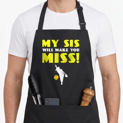 Softball nun apron - Yellow text MY SIS WILL MAKE YOU MISS above white pitcher silhouette and yellow ball — shown on a black cotton canvas apron against a white background