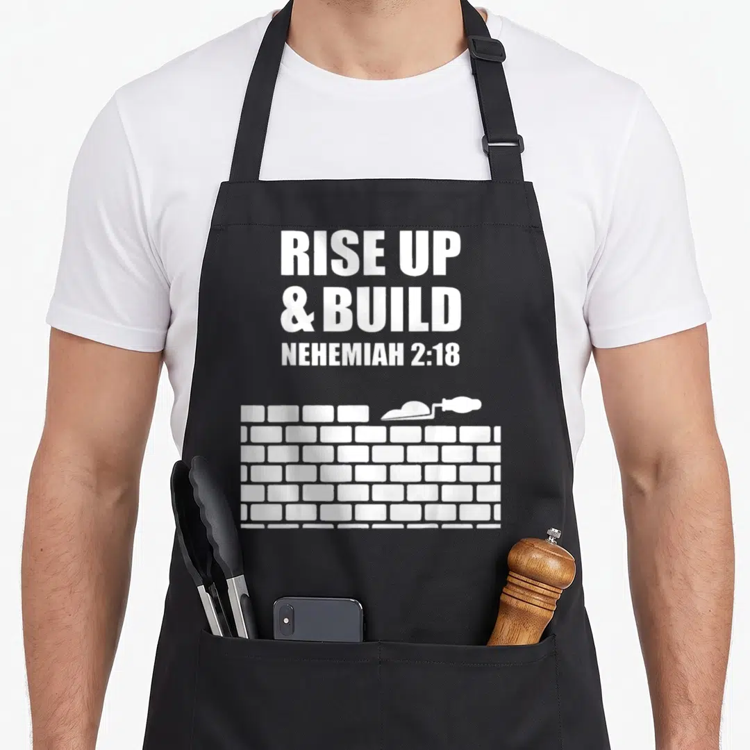 Proverb lettering quotes apron - White text RISE UP BUILD NEHEMIAH 2:18 above brick wall and trowel — shown on a black cotton canvas apron against a white background