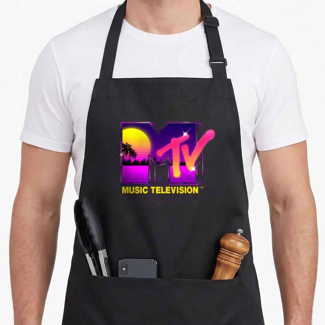 Retrowave 80s apron - MTV logo with 3D M containing synthwave sunset, palm trees, city, and MUSIC TELEVISION text — shown on a black cotton canvas apron against a white background