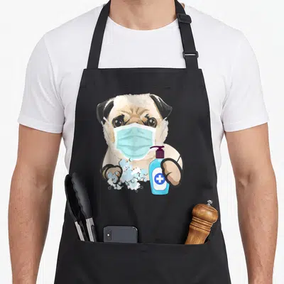 Mask dog face apron - Cartoon pug in blue mask holding soap bottle with bubbles, beige fur, black ears, purple pump — shown on a black cotton canvas apron against a white background