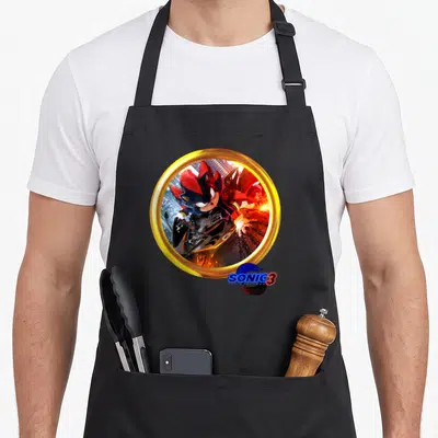 Shadow motorcycle apron - Photo of Shadow the Hedgehog on a bike inside a gold ring with SONIC 3 logo — shown on a black cotton canvas apron against a white background