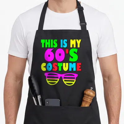 70s 60s apron - Multi-colored text reading THIS IS MY 60S COSTUME above pink and yellow shutter shades — shown on a black cotton canvas apron against a white background