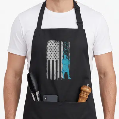 Bagpiper apron or apron - Blue bagpiper silhouette overlaid on distressed white USA flag with floating musical notes — shown on a black cotton canvas apron against a white background