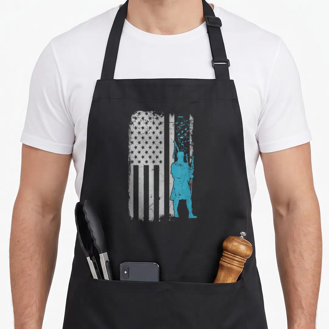 Bagpiper apron or apron - Blue bagpiper silhouette overlaid on distressed white USA flag with floating musical notes — shown on a black cotton canvas apron against a white background
