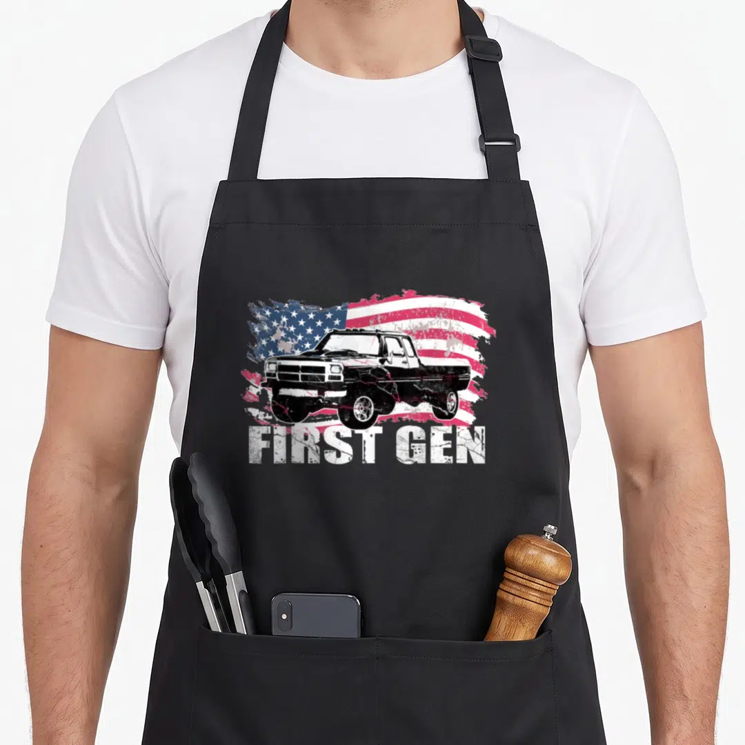 Gen truck apron - Distressed American flag behind a black and white pickup truck with FIRST GEN text below — shown on a black cotton canvas apron against a white background