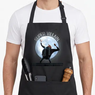Villain despicable me apron - SUPER VILLAIN text over full moon with raised arms character on black platform — shown on a black cotton canvas apron against a white background