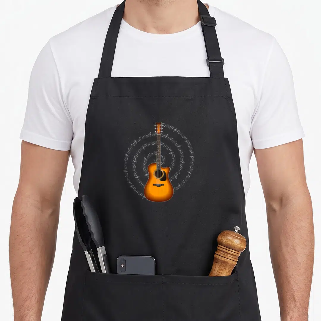 Acoustic themed aprons - Realistic orange acoustic guitar with white musical notes spiraling outward — shown on a black cotton canvas apron against a white background