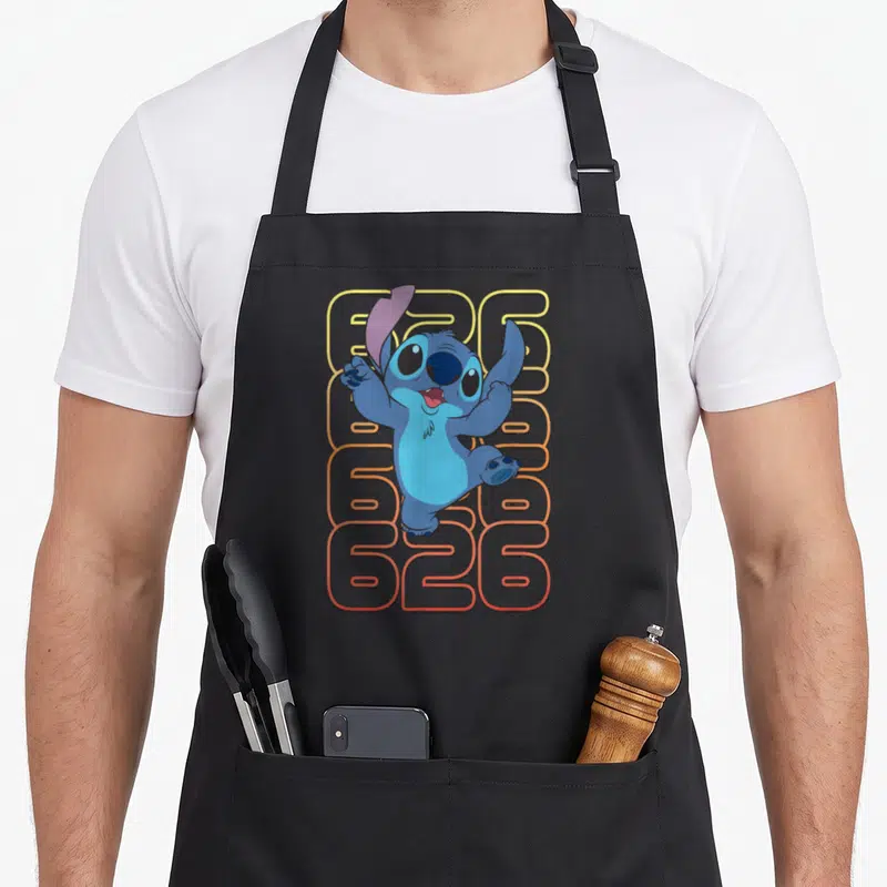 Experiment stitch apron - Blue Stitch character over four stacked 626 rows yellow to red gradient — shown on a black cotton canvas apron against a white background