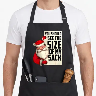 Should santa apron - Santa peeking from behind sign reading YOU SHOULD SEE THE SIZE OF MY SACK — shown on a black cotton canvas apron against a white background