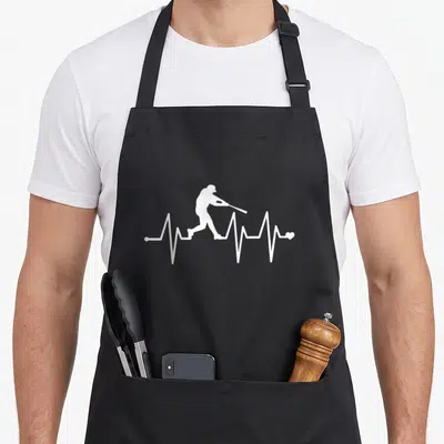 Pulse baseball apron - white batter silhouette inside a heartbeat line ending in a small heart — shown on a black cotton canvas apron against a white background