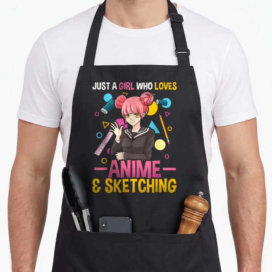 Retro hobby anime apron - Anime girl with pink hair holding a ruler surrounded by art supplies and text — shown on a black cotton canvas apron against a white background