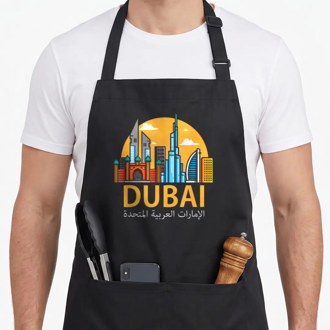 Dubai emirati apron - Minimalist Dubai skyline with yellow sun and bilingual text in English and Arabic script — shown on a black cotton canvas apron against a white background