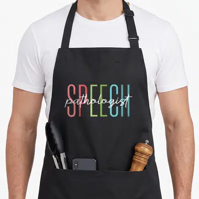 Speech language my therapy apron - Colorful block letters spelling SPEECH with white pathologist script overlay — shown on a black cotton canvas apron against a white background