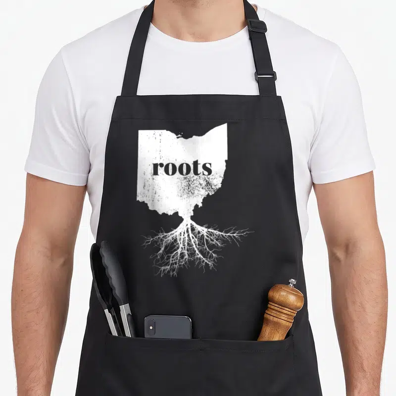 Ohio root pride apron - White Ohio map silhouette with roots text and branching roots on grey background — shown on a black cotton canvas apron against a white background