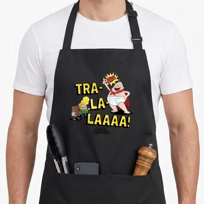 Epic captain apron - Captain Underpants cartoon with yellow Tra-La-Laaa text and two small boys — shown on a black cotton canvas apron against a white background