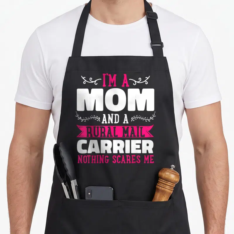 Rural mother's day aprons - I'm a Mom Rural Mail Carrier text with pink ribbon and white swirls — shown on a black cotton canvas apron against a white background