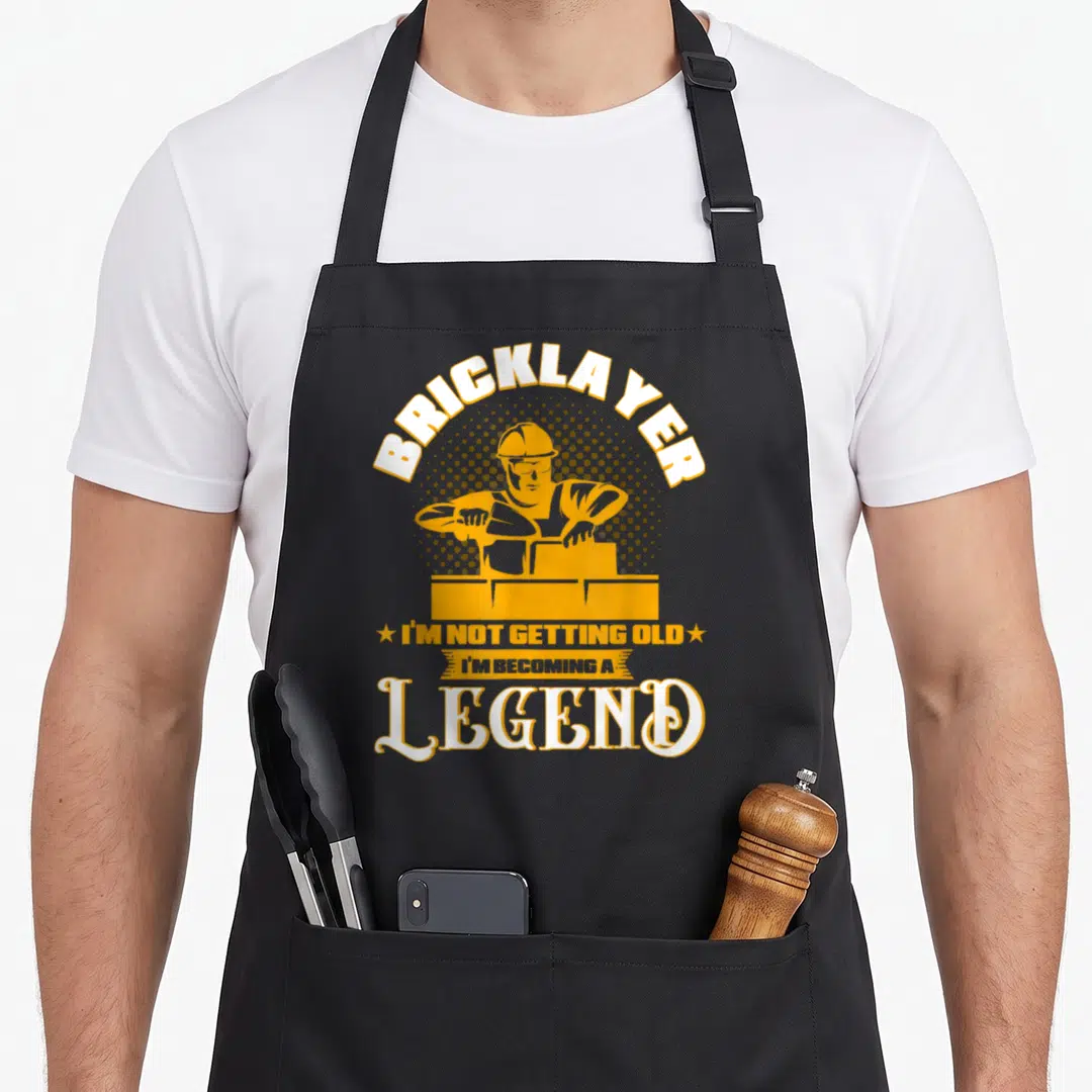 Getting bricklayer apron - Retro bricklayer illustration with I'm Not Getting Old I'm Becoming A Legend text in yellow — shown on a black cotton canvas apron against a white background