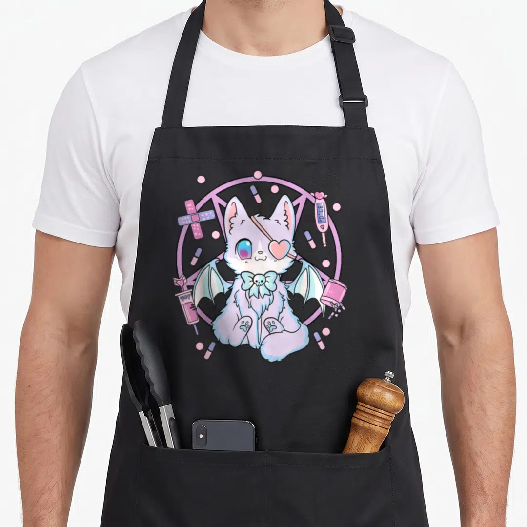 Yami cat apron - Winged cat with eyepatch and medical items like pills and syringe in pastel colors — shown on a black cotton canvas apron against a white background