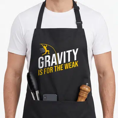 Pole basin utpb apron - Gravity Is For The Weak text with yellow vaulting silhouette and white lettering — shown on a black cotton canvas apron against a white background
