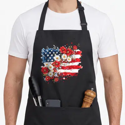 Wildflower 4th of july apron - Watercolor USA flag intertwined with red white flowers and green leaves — shown on a black cotton canvas apron against a white background