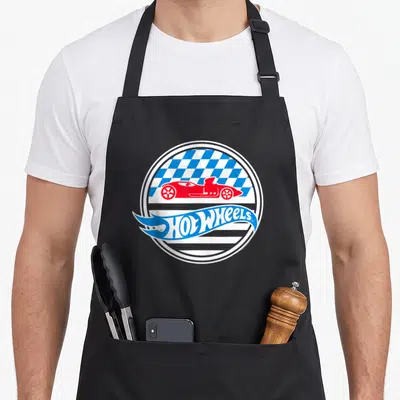 Star wheel apron - Red race car over blue and white checkered circle with flame Hot Wheels text logo — shown on a black cotton canvas apron against a white background