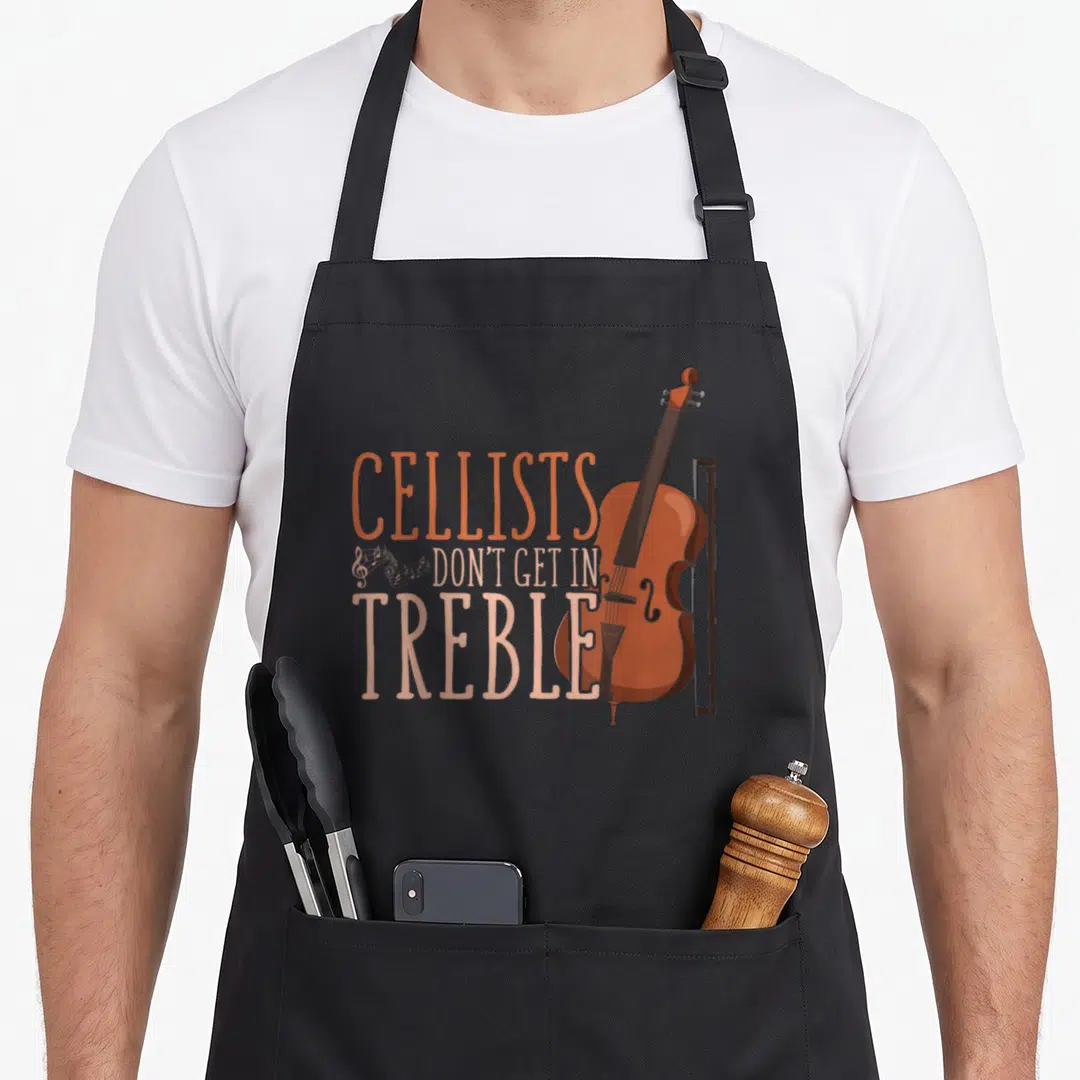 Trouble cello apron - Cartoon cello and bow with stacked text CELLISTS DON'T GET IN TREBLE in orange and peach — shown on a black cotton canvas apron against a white background