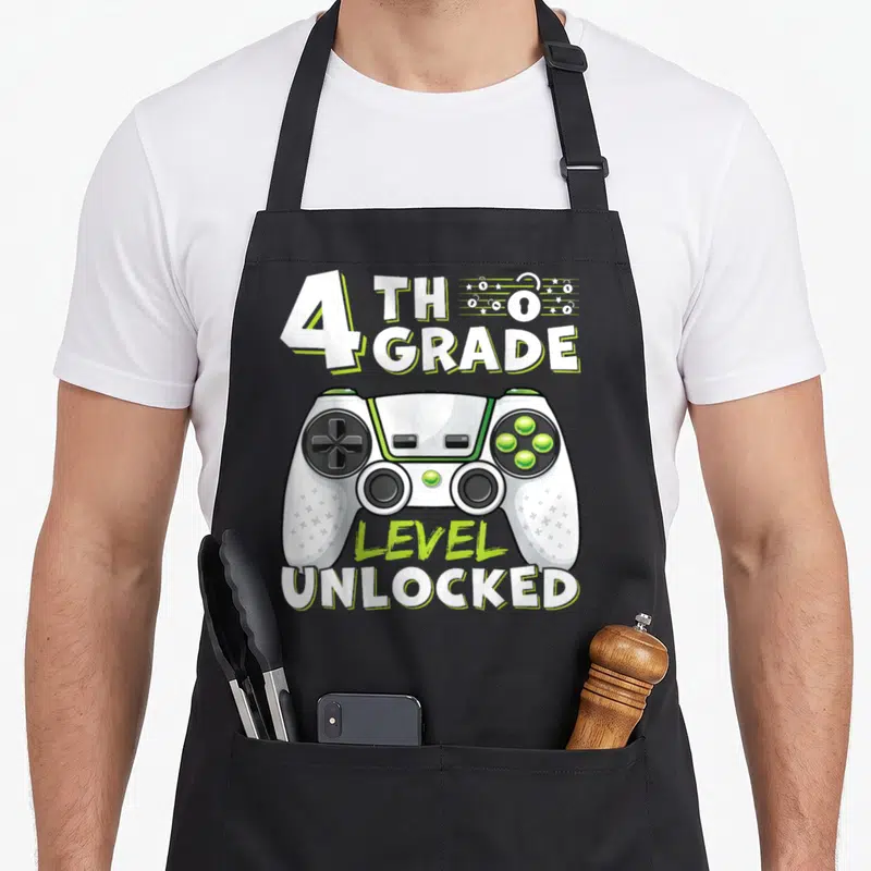 4th day fourth apron - White lime green game controller with 4th Grade Level Unlocked text and lock icons — shown on a black cotton canvas apron against a white background