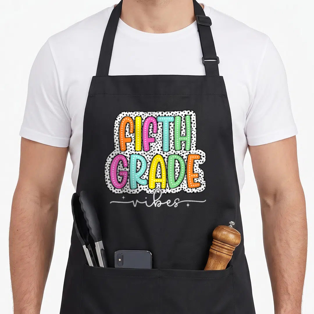5th dot apron - Colorful FIFTH GRADE vibes text on white shape with black polka dots — shown on a black cotton canvas apron against a white background