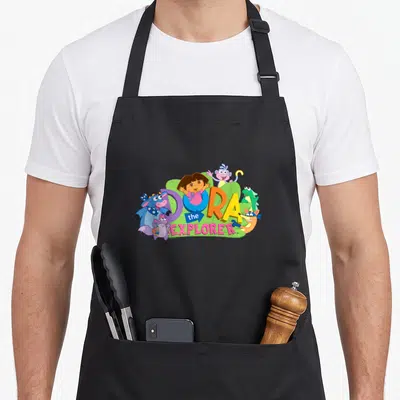Swiper explorer apron - Dora the Explorer logo with Boots Tico Isa and Swiper in purple blue green yellow and pink — shown on a black cotton canvas apron against a white background
