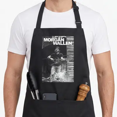 Morgan country girl apron - Grayscale photo of man playing guitar by fire with MORGAN WALLEN text — shown on a black cotton canvas apron against a white background