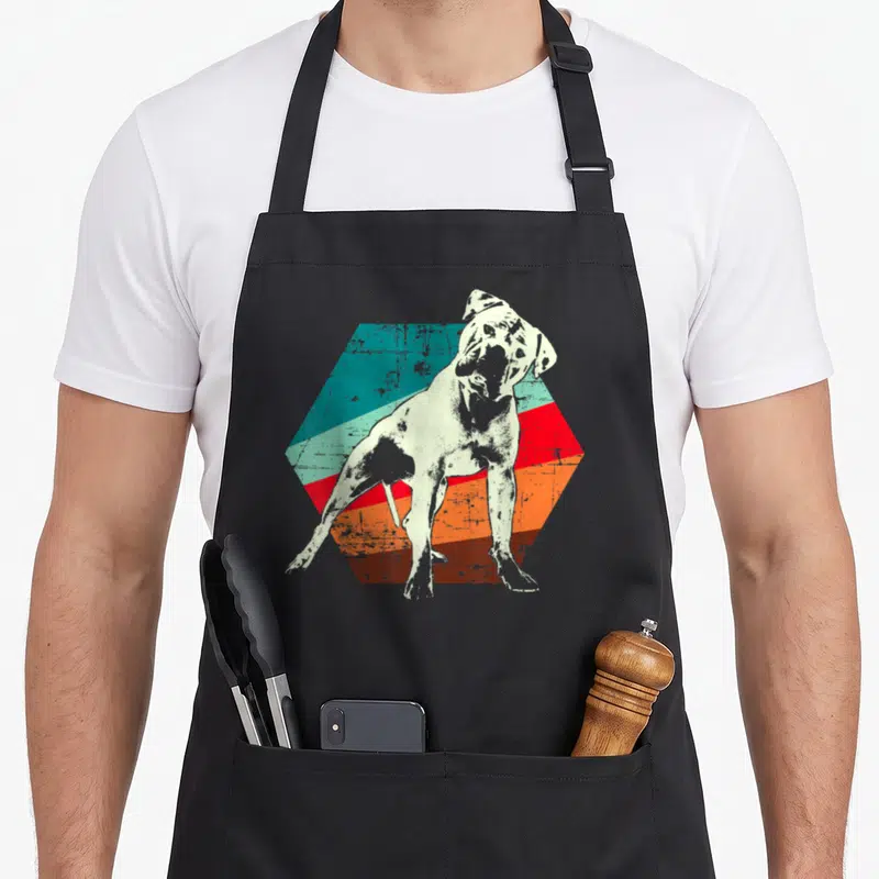 Funny bulldog southern aprons - Distressed white bulldog standing on a striped teal red orange brown hexagon — shown on a black cotton canvas apron against a white background