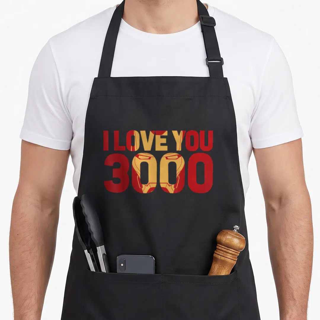 Fill general apron - Red and yellow typography with Iron Man mask filling the words I Love You 3000 — shown on a black cotton canvas apron against a white background