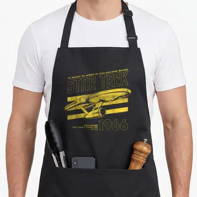 Original collegiate aprons - Yellow Star Trek Enterprise ship over three lines with 1966 text — shown on a black cotton canvas apron against a white background