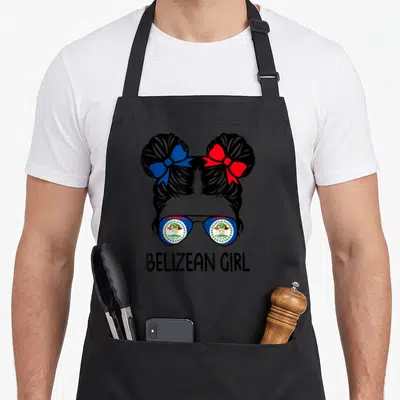 Belizean messy aprons - Cartoon girl head with two buns and flag sunglasses below BELIZEAN GIRL text — shown on a black cotton canvas apron against a white background