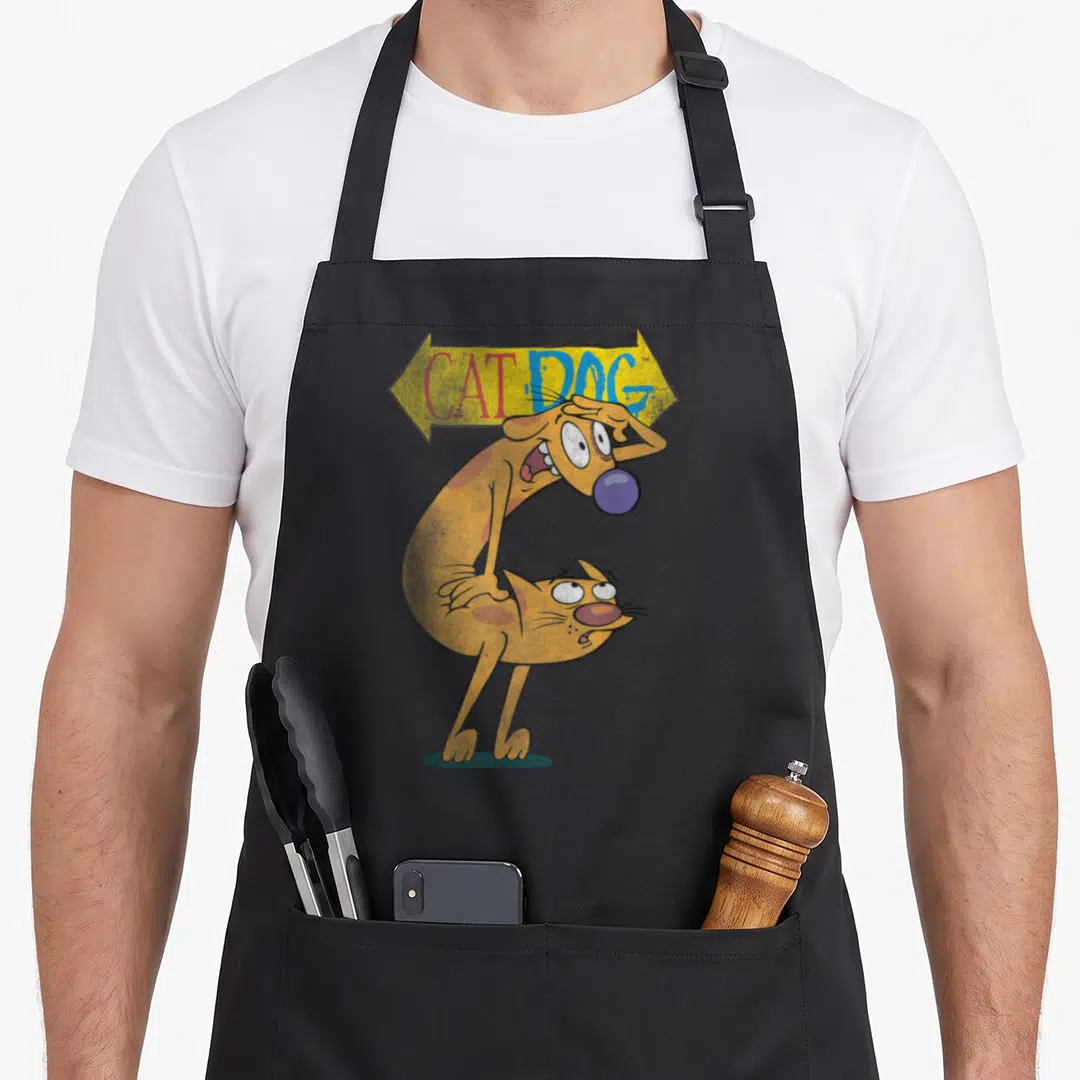 Catdog character aprons - Yellow arrow sign with CAT DOG text above orange two-headed cartoon character saluting — shown on a black cotton canvas apron against a white background