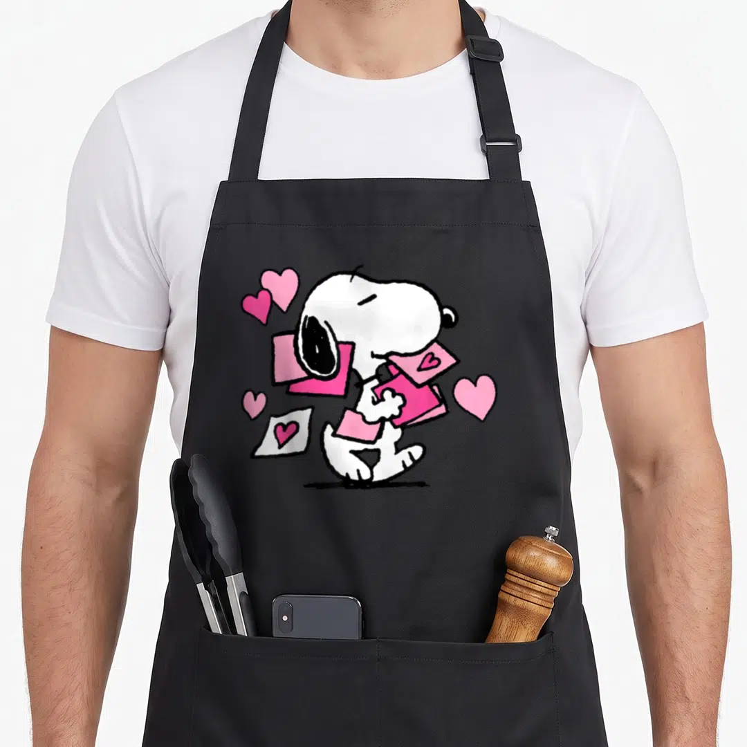 Letter valentine apron - White cartoon dog holding pink envelopes surrounded by pink hearts — shown on a black cotton canvas apron against a white background