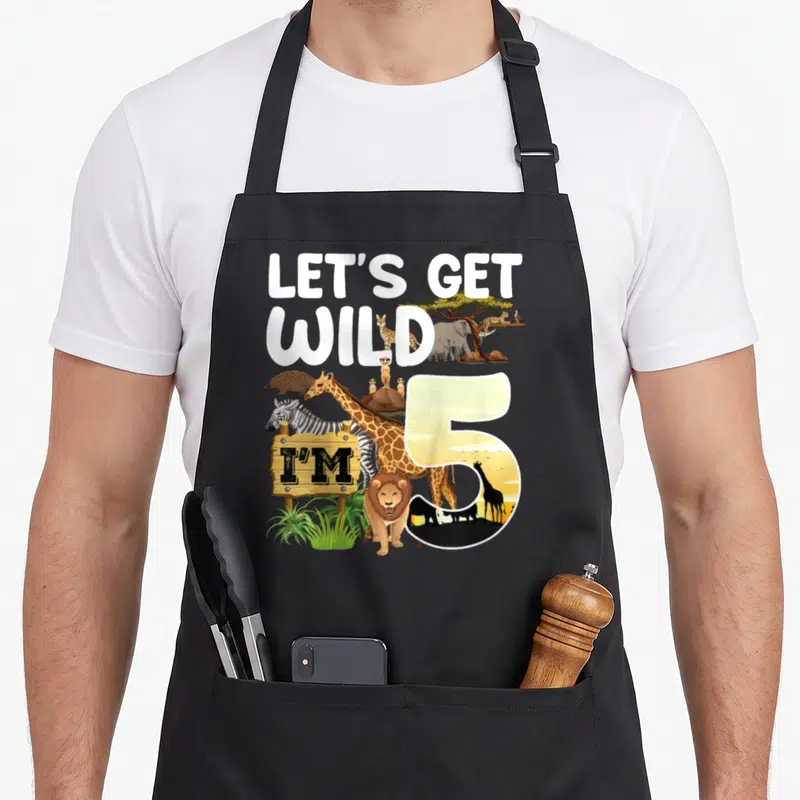 Safari jungle birthday apron - LET'S GET WILD I'M 5 with lion giraffe zebra and wooden sign — shown on a black cotton canvas apron against a white background