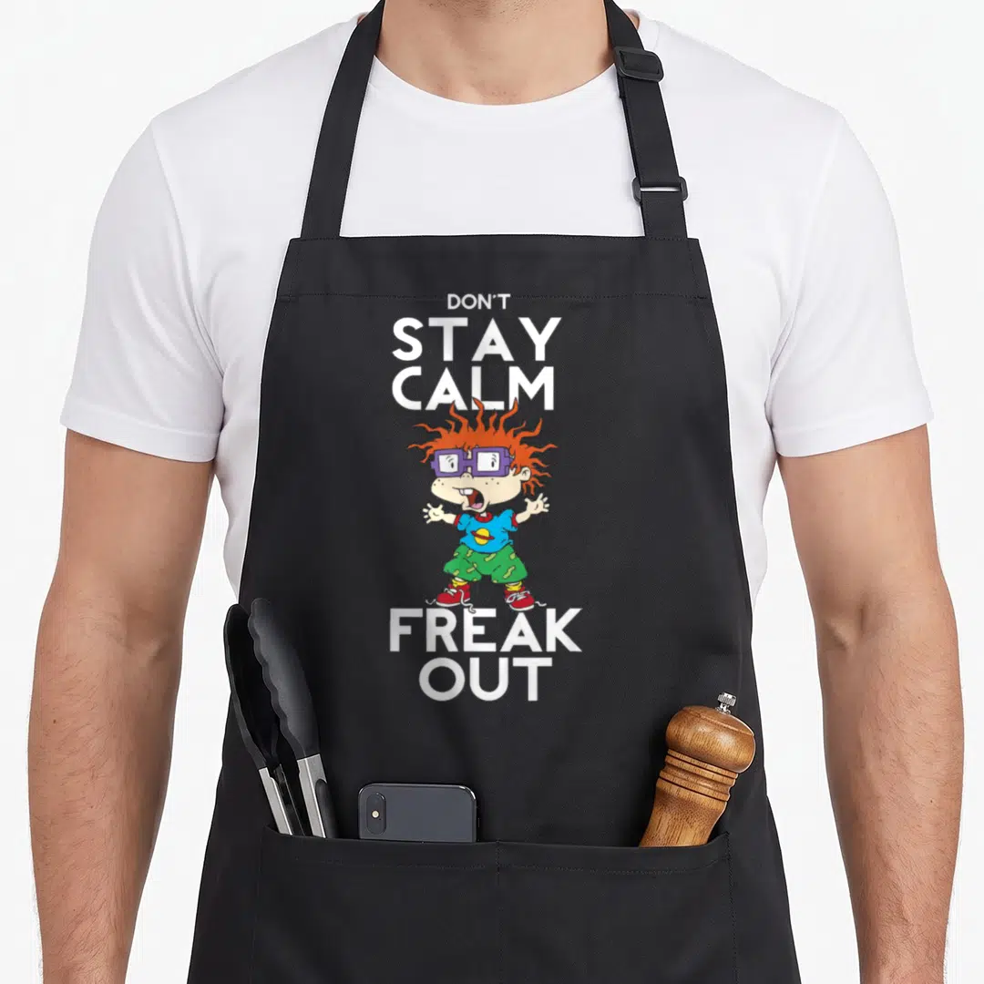 Chuckie creative writing apron - Cartoon boy with orange hair between white text reading DON'T STAY CALM FREAK OUT — shown on a black cotton canvas apron against a white background